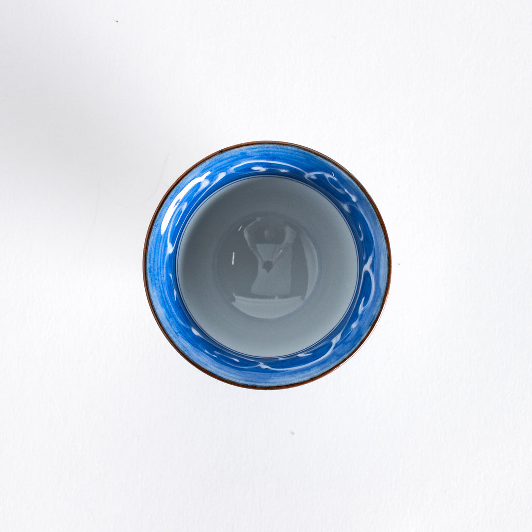 Top view of a blue and white porcelain sake cup, showing the intricate hand-painted wave pattern inside the cup.