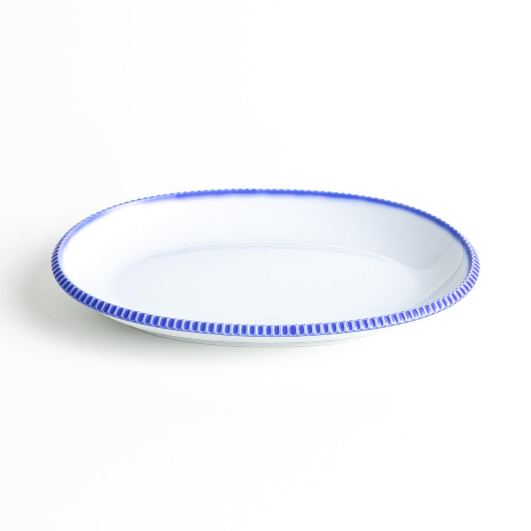 An oval-shaped white dinner plate with a rustic scallop-edged design. The border comes in blue, brown, and olive.