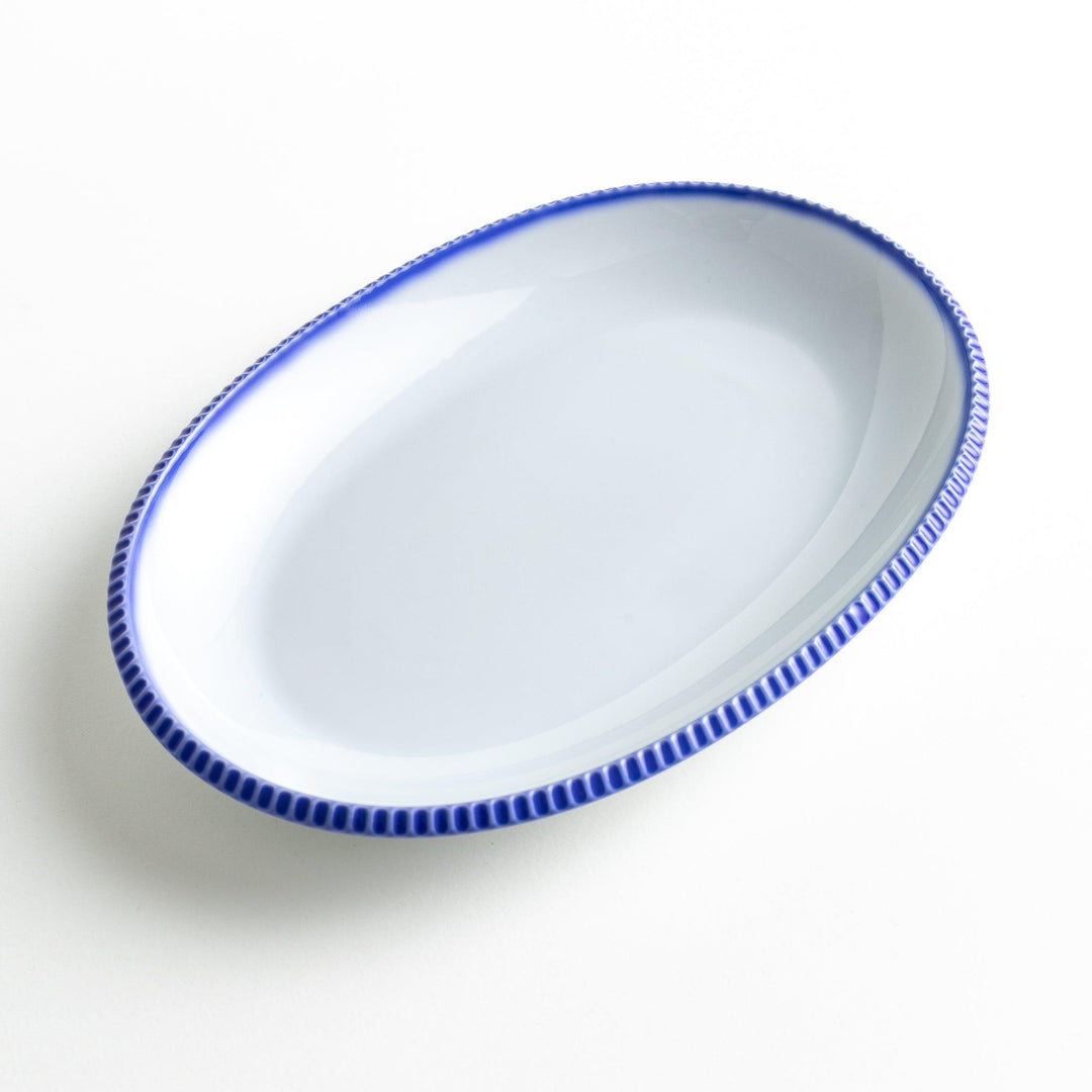 An oval-shaped white dinner plate with a rustic scallop-edged design. The border comes in blue, brown, and olive.