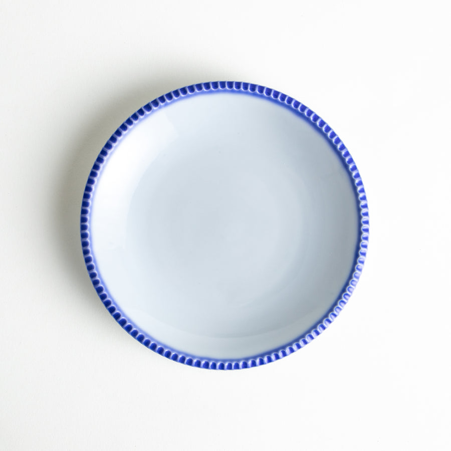 A round white dessert plate with a rustic scallop-edged border. The border comes in blue, brown, and olive.