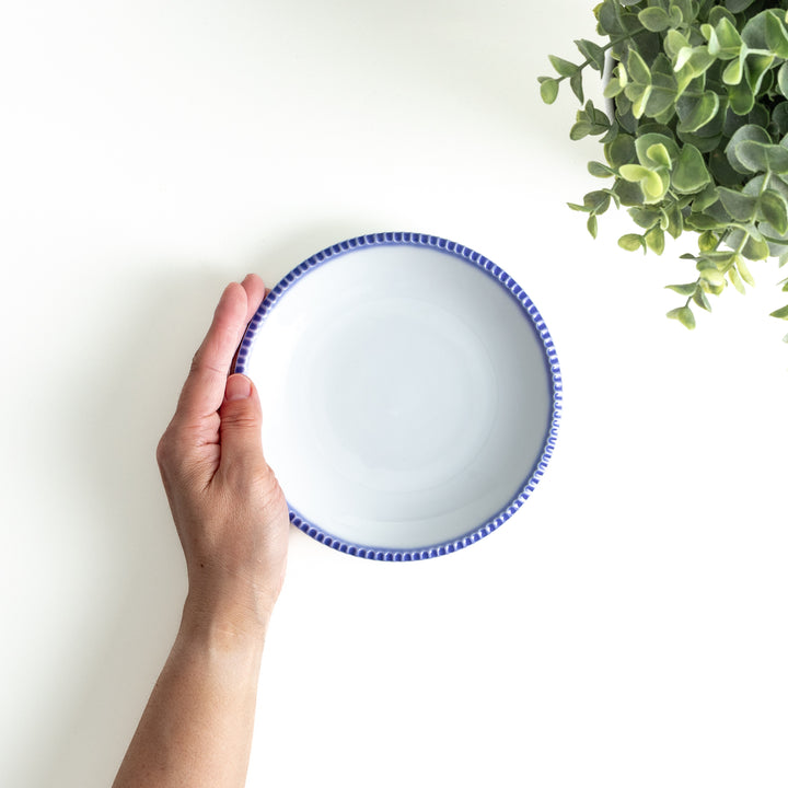 A round white dessert plate with a rustic scallop-edged border. The border comes in blue, brown, and olive.