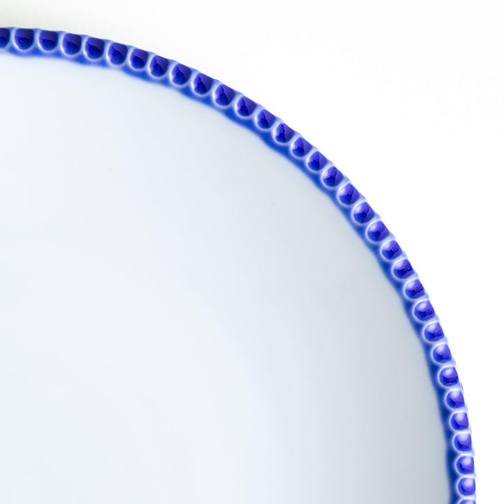 A round white dinner plate with a rustic scallop-edged border. The border comes in blue, brown, and olive.