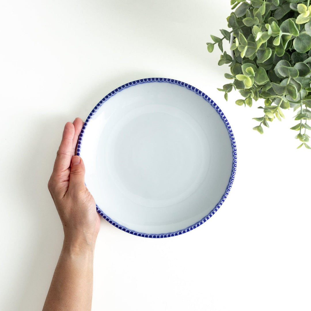 A round white dinner plate with a rustic scallop-edged border. The border comes in blue, brown, and olive.