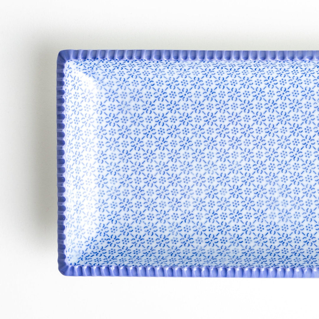 A rectangular ceramic plate with a fine blue floral pattern, bordered by a textured blue rim.