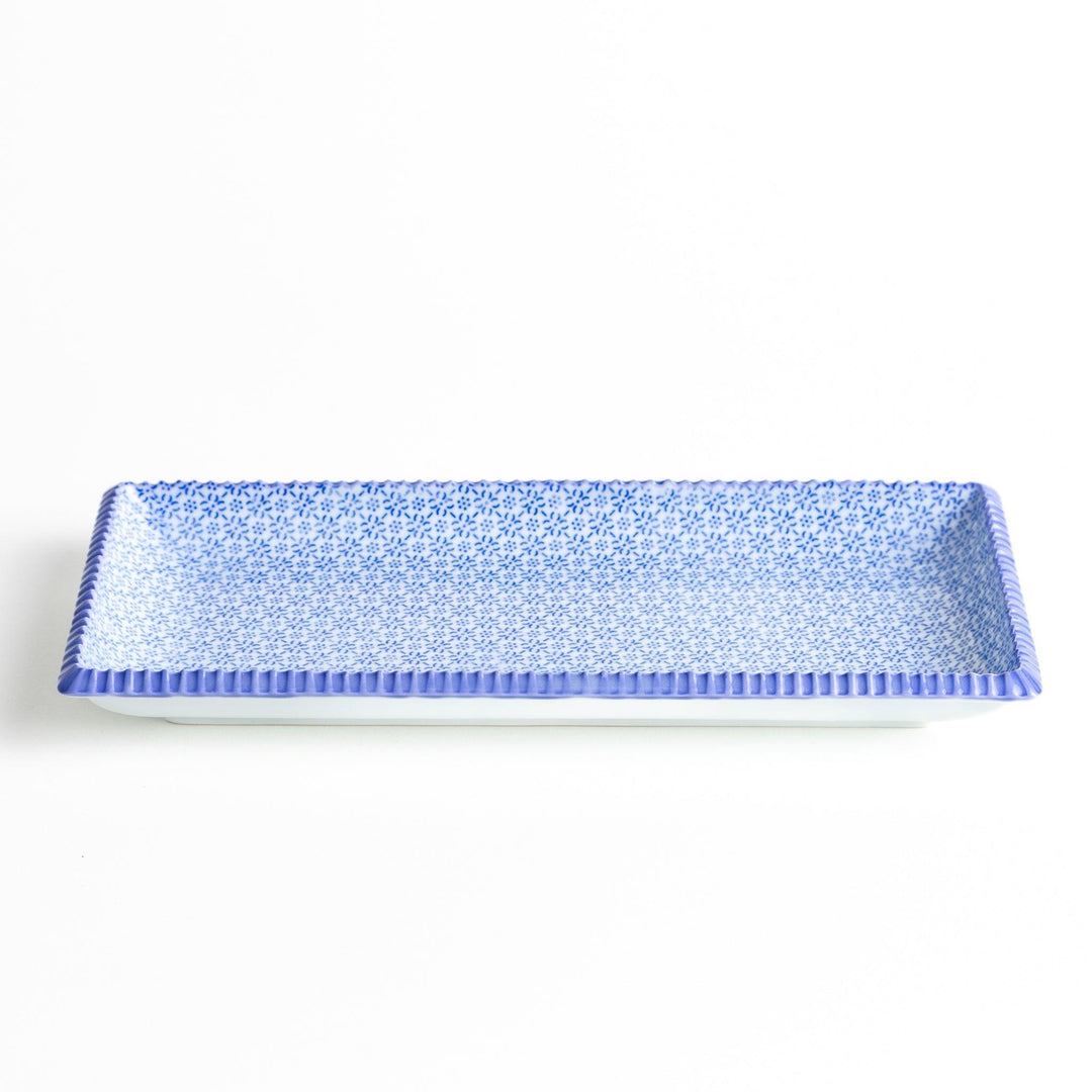 A rectangular ceramic plate with a fine blue floral pattern, bordered by a textured blue rim.