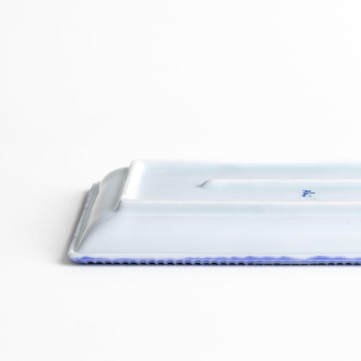 A rectangular ceramic plate with a fine blue floral pattern, bordered by a textured blue rim.