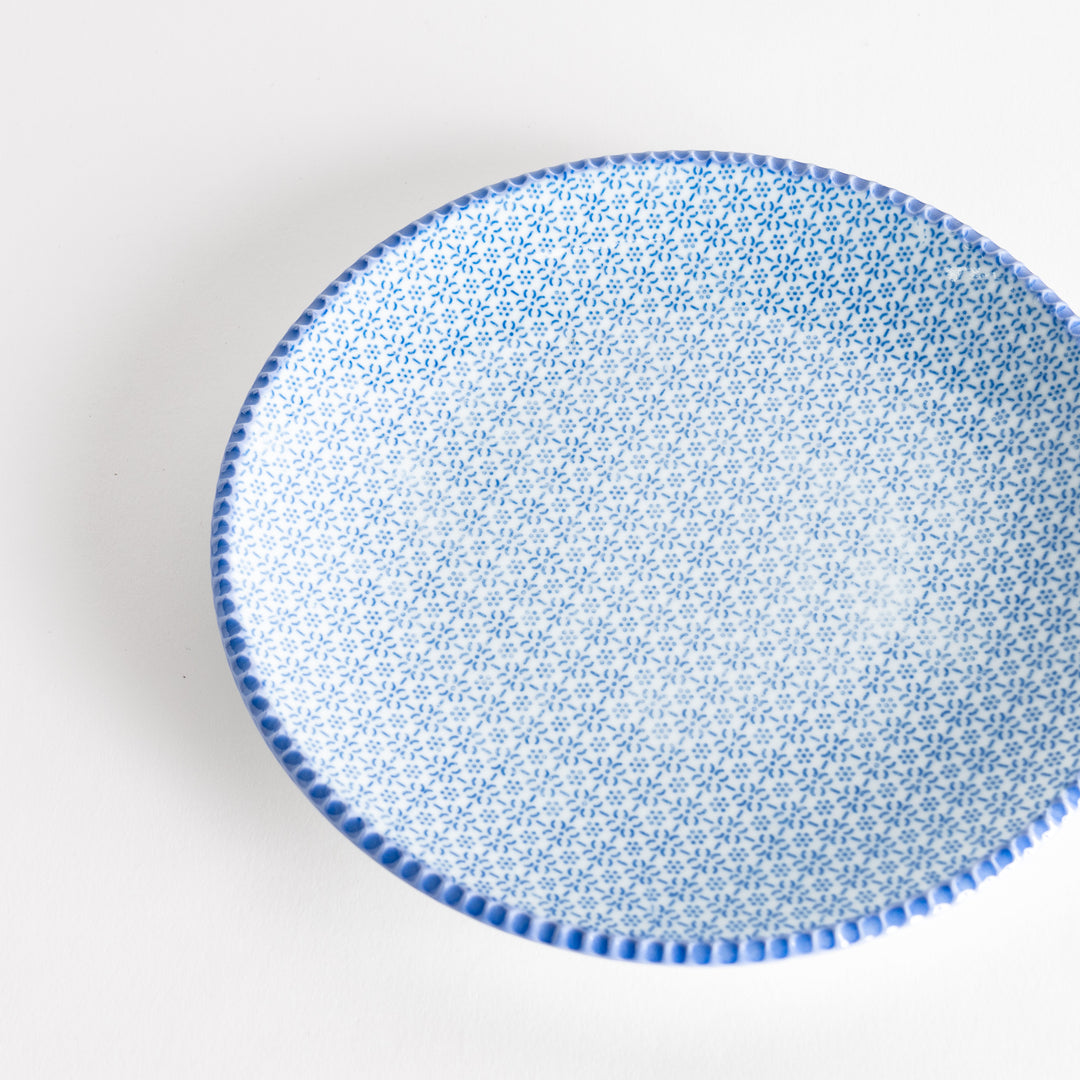 Close-up top view of the blue sesame salad plate, featuring a delicate pattern of blue flowers and a textured rim.