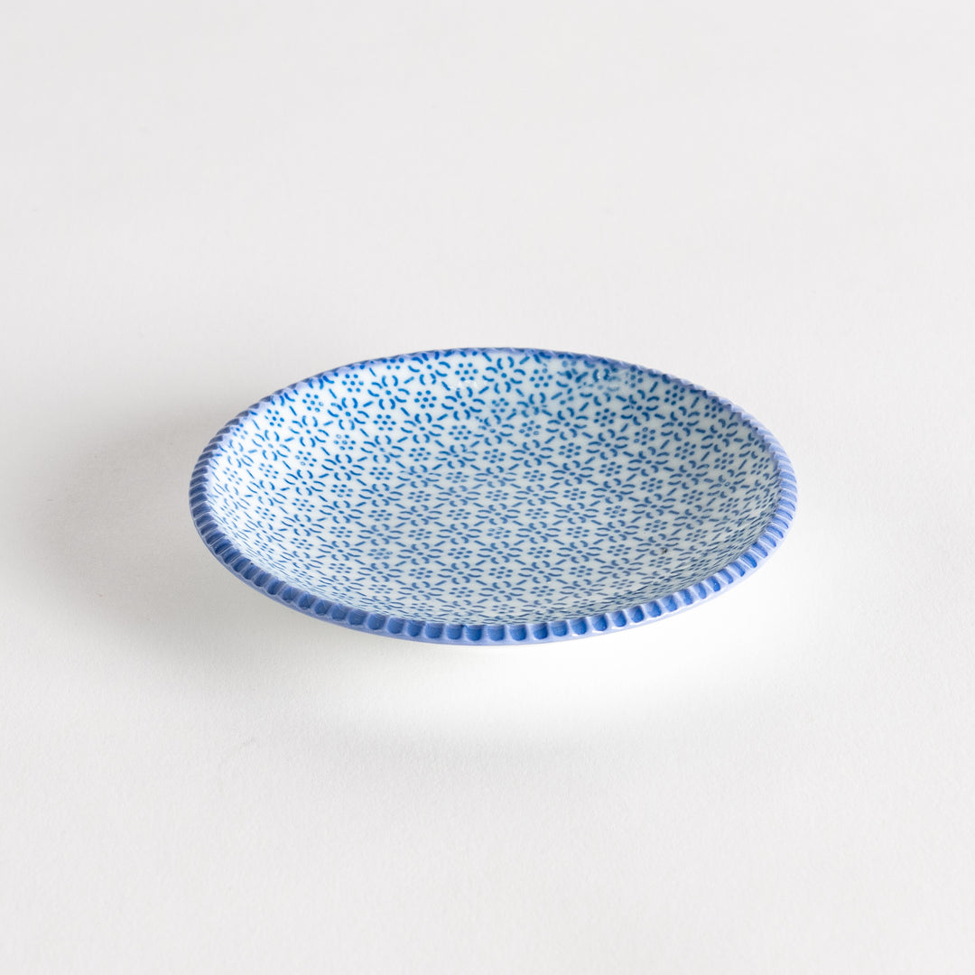 A round ceramic plate with a delicate blue floral pattern, bordered by a textured rim.