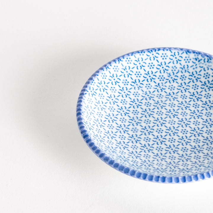 A round ceramic plate with a delicate blue floral pattern, bordered by a textured rim.