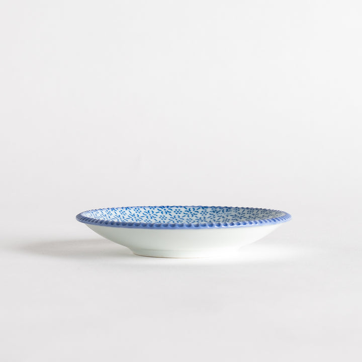 A round ceramic plate with a delicate blue floral pattern, bordered by a textured rim.