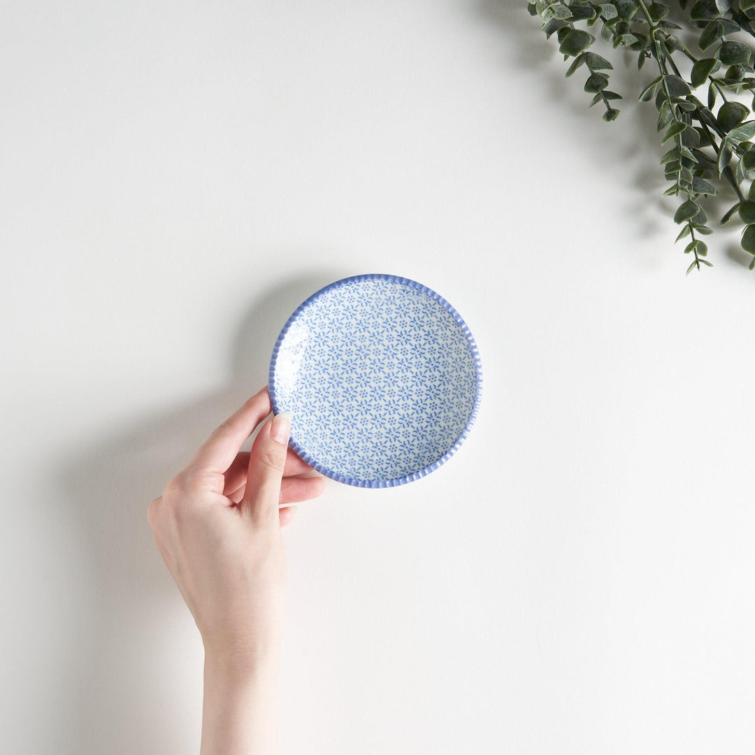 A round ceramic plate with a delicate blue floral pattern, bordered by a textured rim.