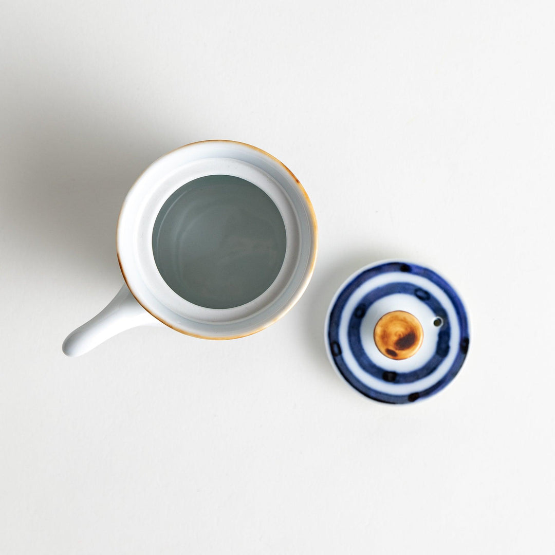 A small white ceramic soy sauce dispenser featuring blue horizontal stripes.