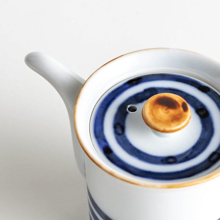 A small white ceramic soy sauce dispenser featuring blue horizontal stripes.