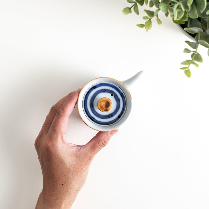 A small white ceramic soy sauce dispenser featuring blue horizontal stripes.