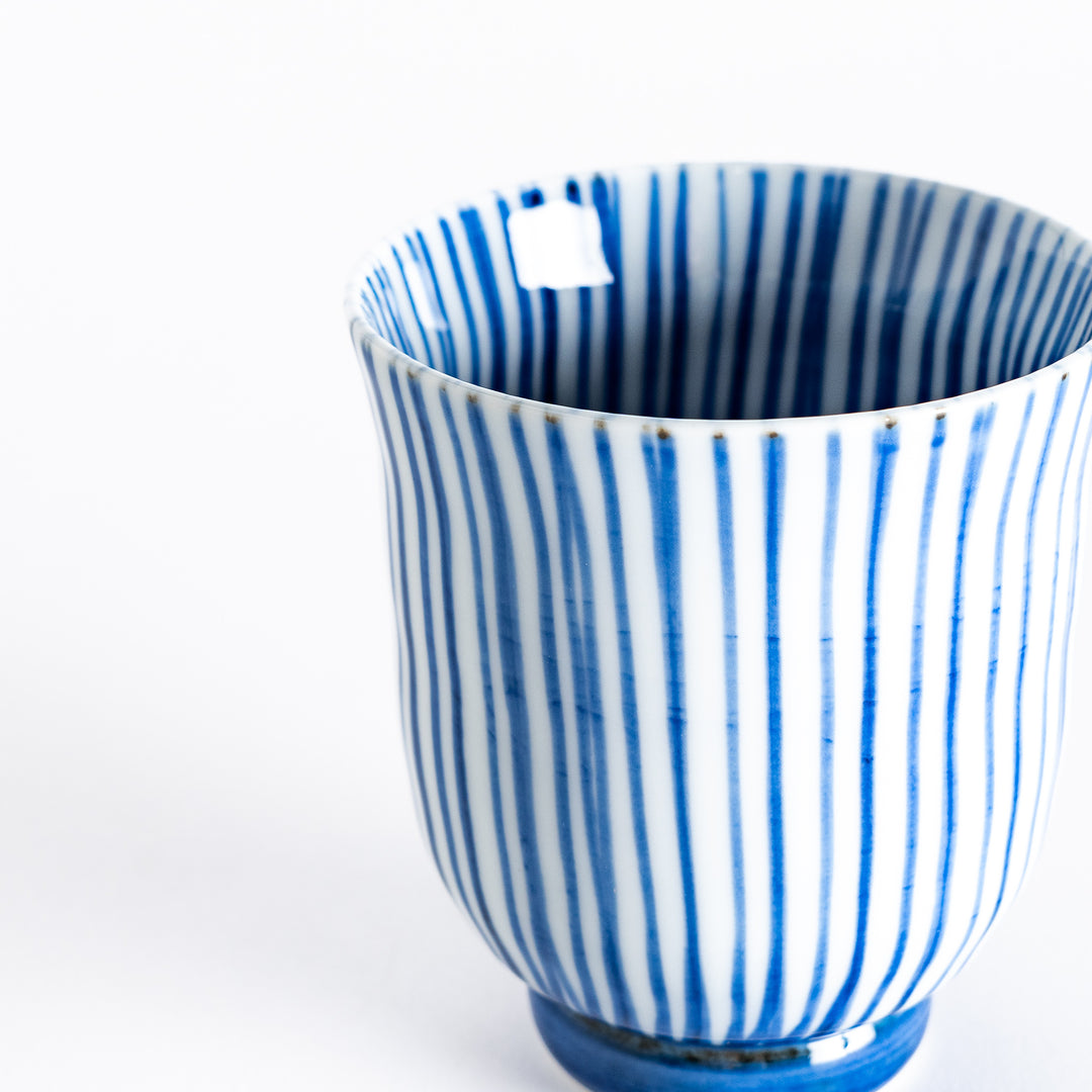 Close-up of the blue-striped tea cup's detailed vertical lines and smooth porcelain surface.