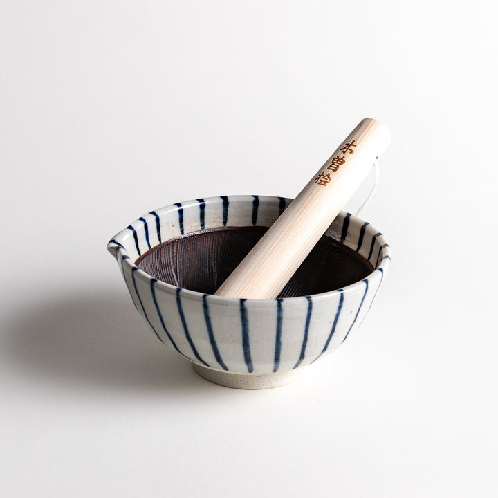 Blue-striped ceramic mortar with a wooden pestle, featuring a deep interior with earthy tones, perfect for grinding with style and tradition.