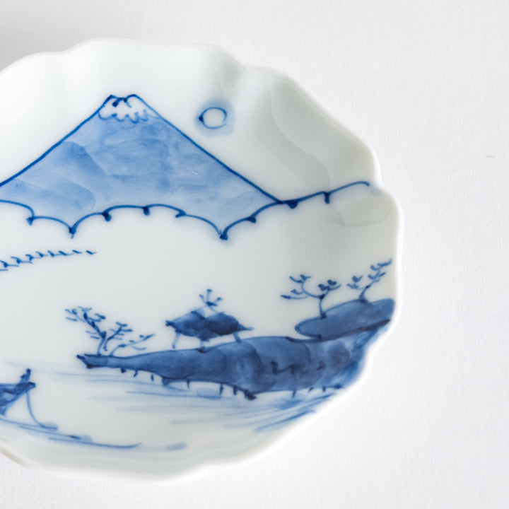 Close-up of a round ceramic dish decorated with Mount Fuji and floral motifs, highlighting its intricate design.