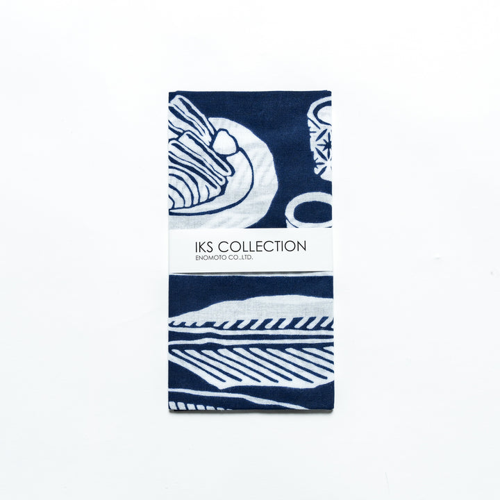 Navy blue tenugui, folded with a product sleeve displaying white fish designs.