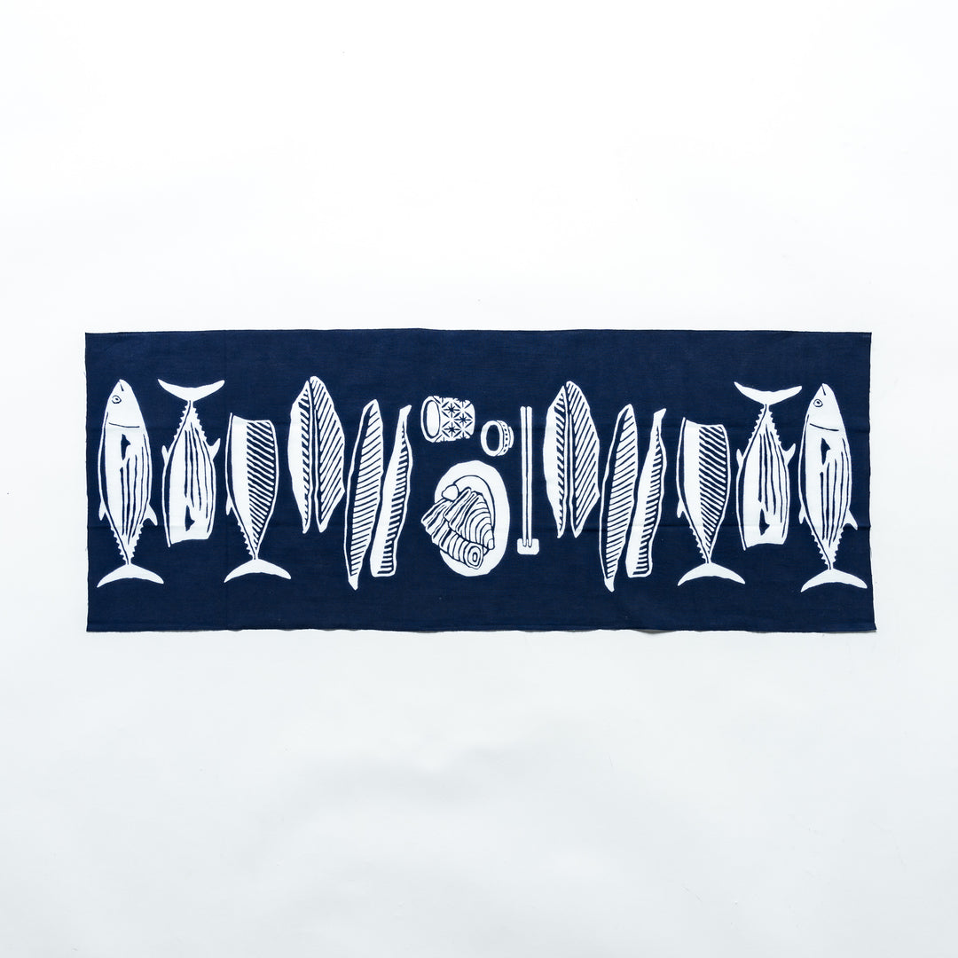 Fully spread navy tenugui hand towel showcasing white fish and wave illustrations.