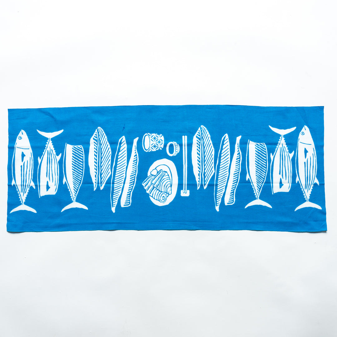 Fully spread light blue tenugui hand towel showcasing white fish and wave illustrations.