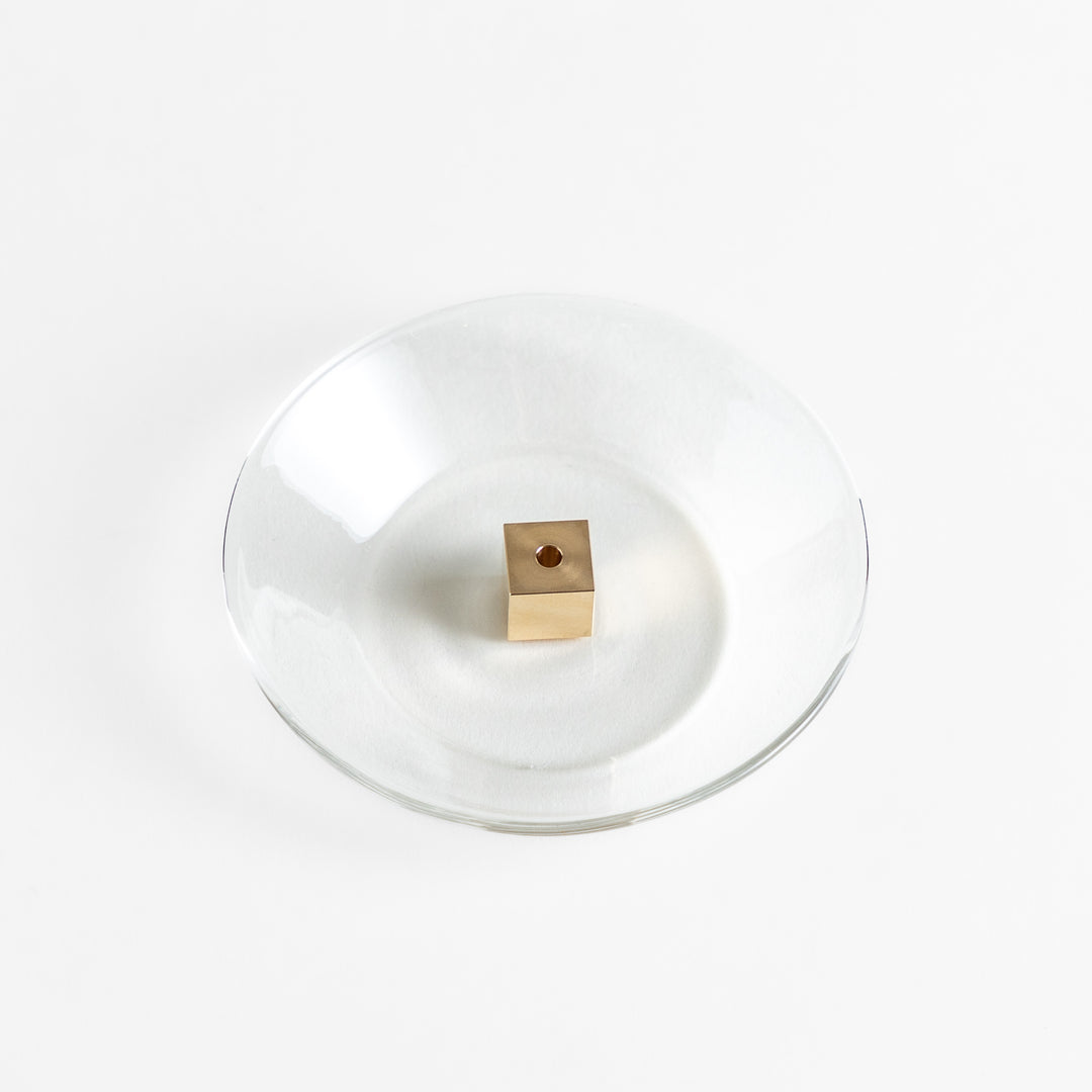 A modern Incense Holder set featuring a transparent glass dish and a brass cube stand, combining minimalist aesthetics with functionality for a refined incense experience.