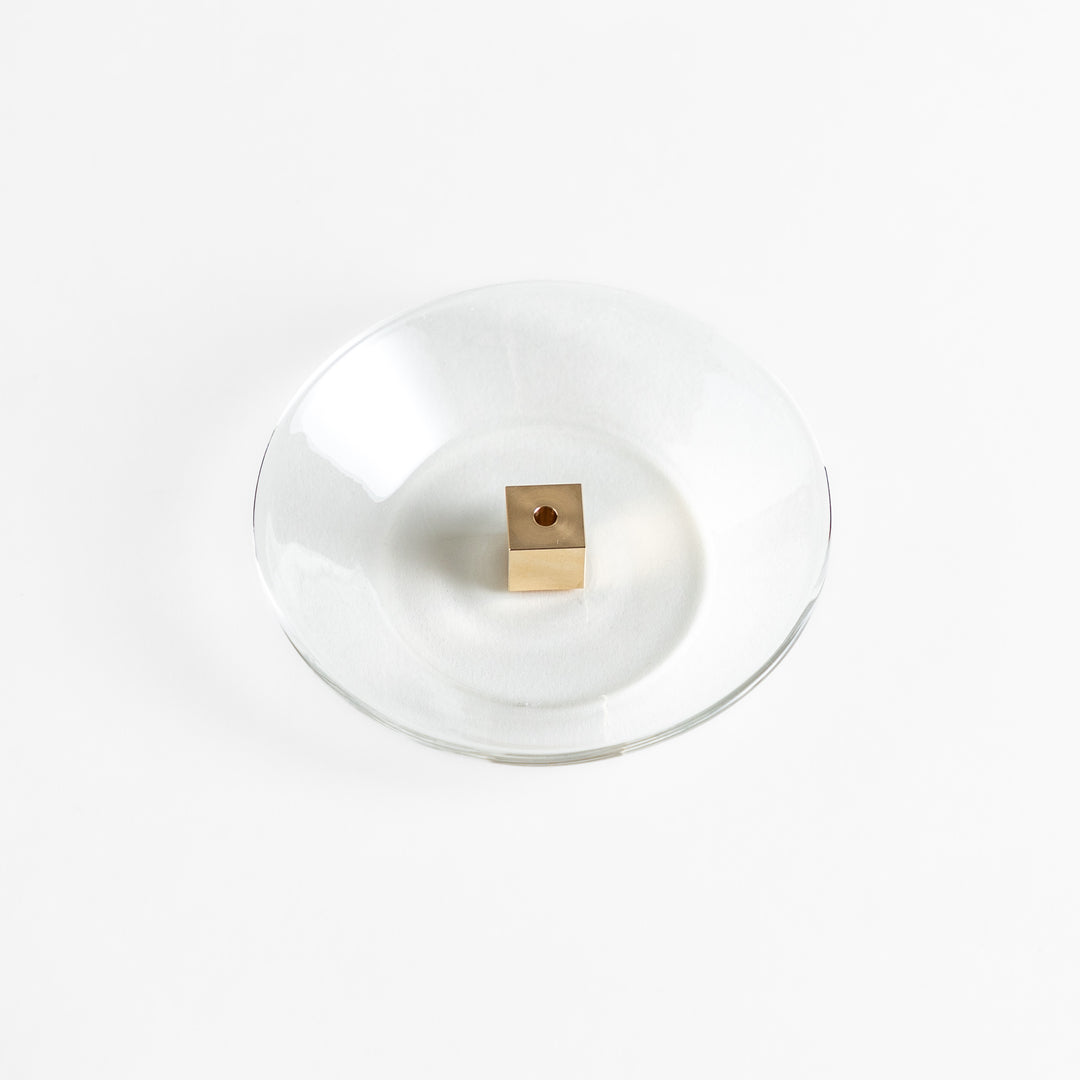 A modern Incense Holder set featuring a transparent glass dish and a brass cube stand, combining minimalist aesthetics with functionality for a refined incense experience.