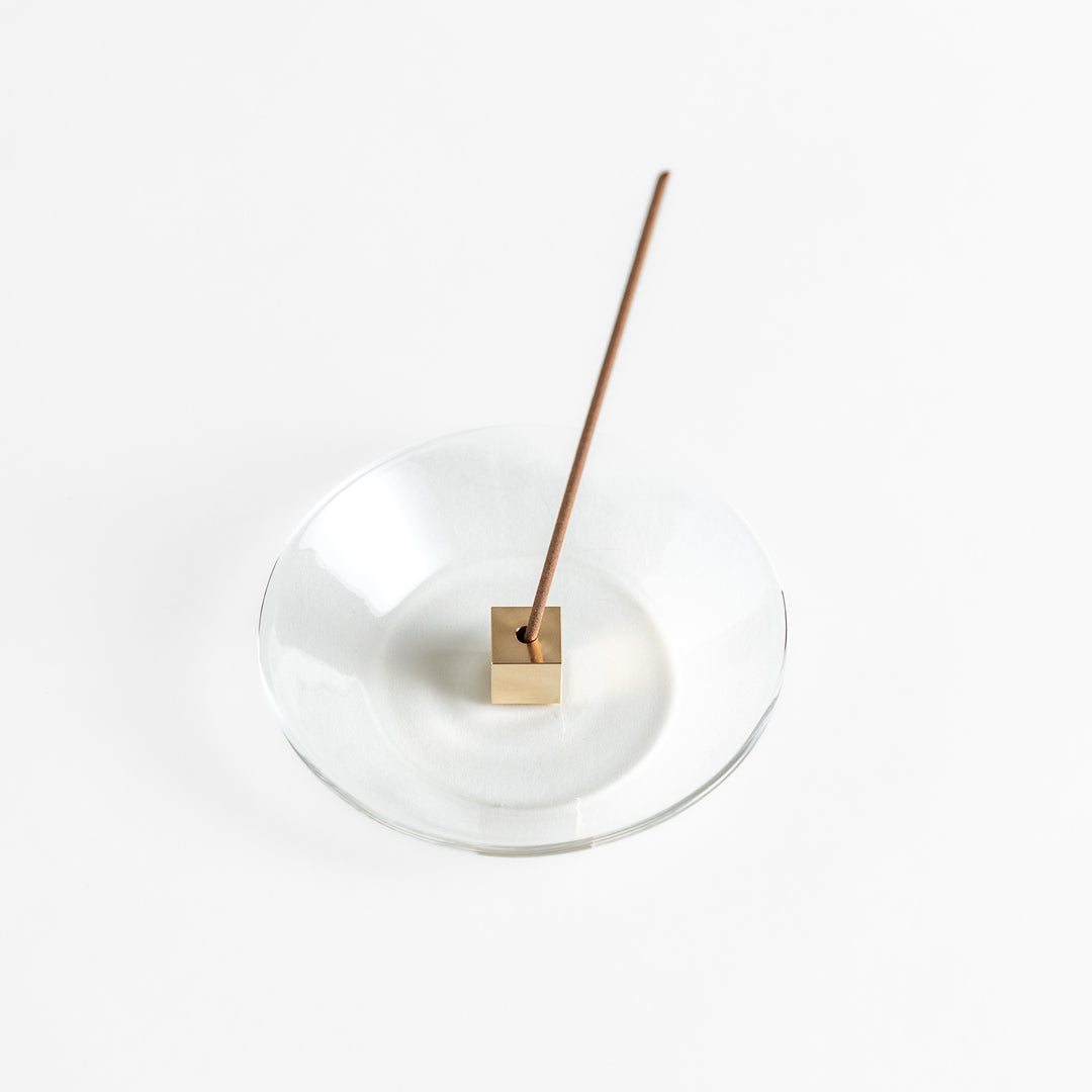 A modern Incense Holder set featuring a transparent glass dish and a brass cube stand, combining minimalist aesthetics with functionality for a refined incense experience.