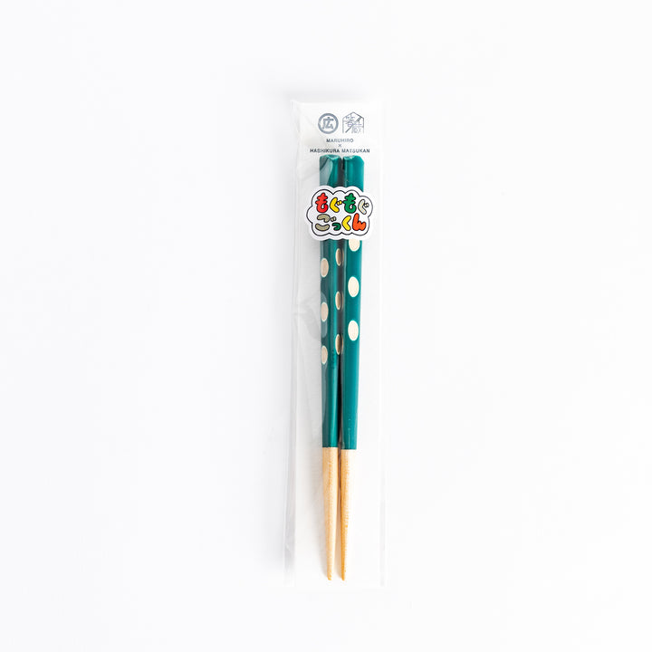 Green children’s chopsticks with white dots, packaged in clear wrapping, showcasing a playful design.