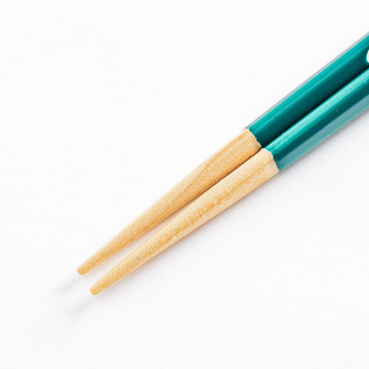 Close-up of the natural wooden tips of the green chopsticks, showing the smooth finish.