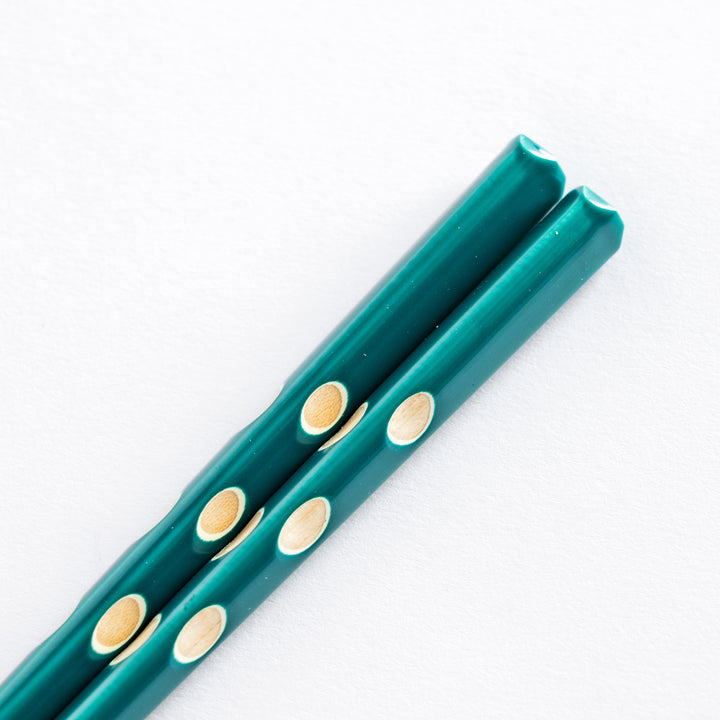 Close-up of the green chopsticks’ handle, featuring white dots and a rounded, textured design.