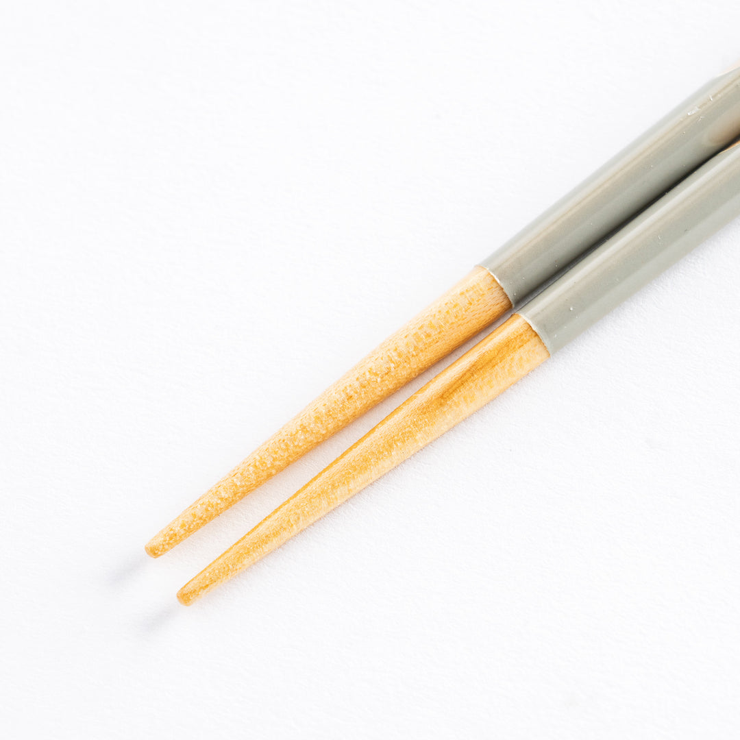 Close-up view of gray chopsticks, showcasing the smooth wooden tips and polka dot details.