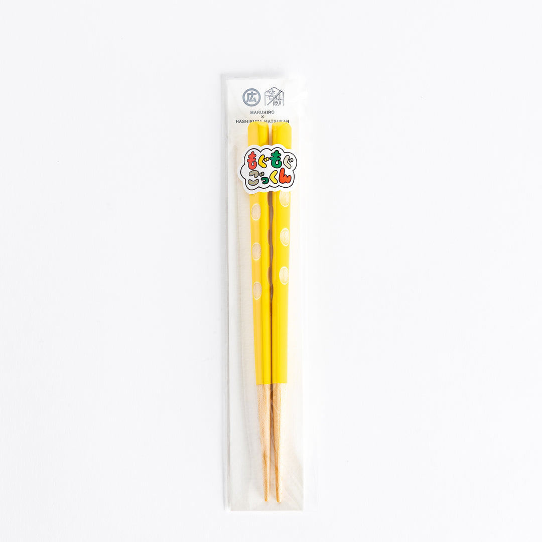 Bright yellow children's chopsticks in packaging, featuring a playful design with polka dots.