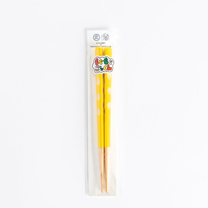 Bright yellow children's chopsticks in packaging, featuring a playful design with polka dots.