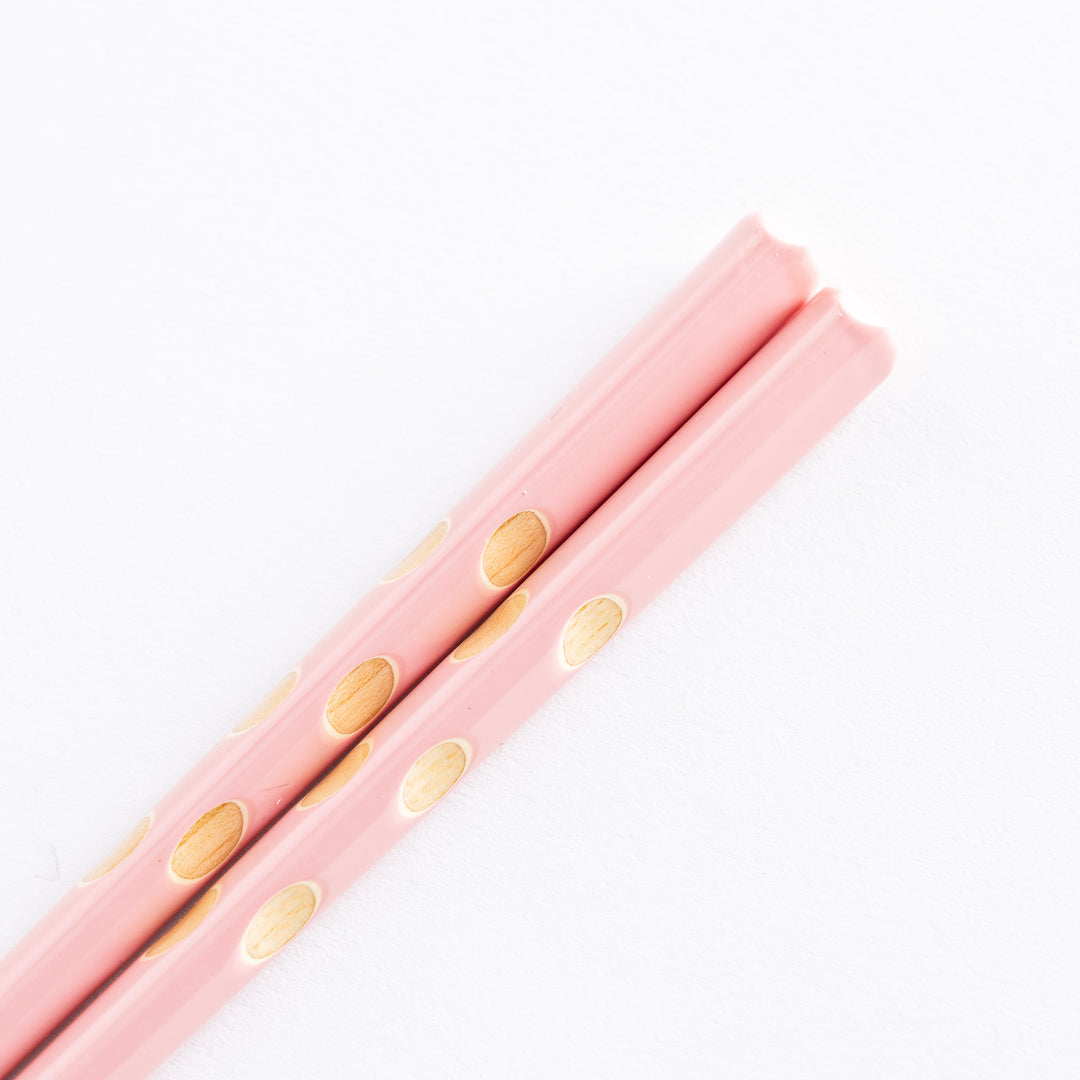 Close-up of pink children’s chopsticks with wood tips and round dot accents.