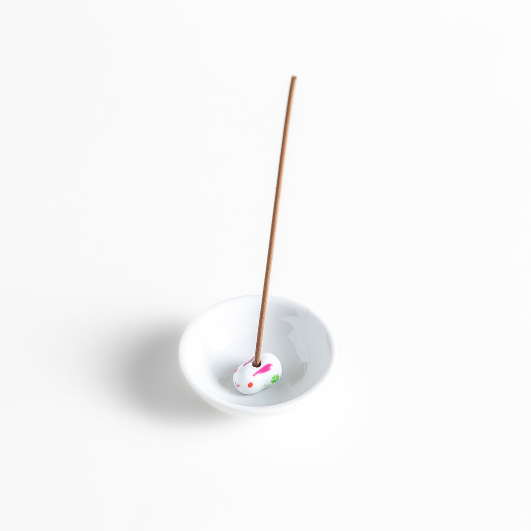 White ceramic incense holder featuring an adorable rabbit-shaped stand with pink and green accents, offering a charming and elegant way to enjoy incense while enhancing any space.