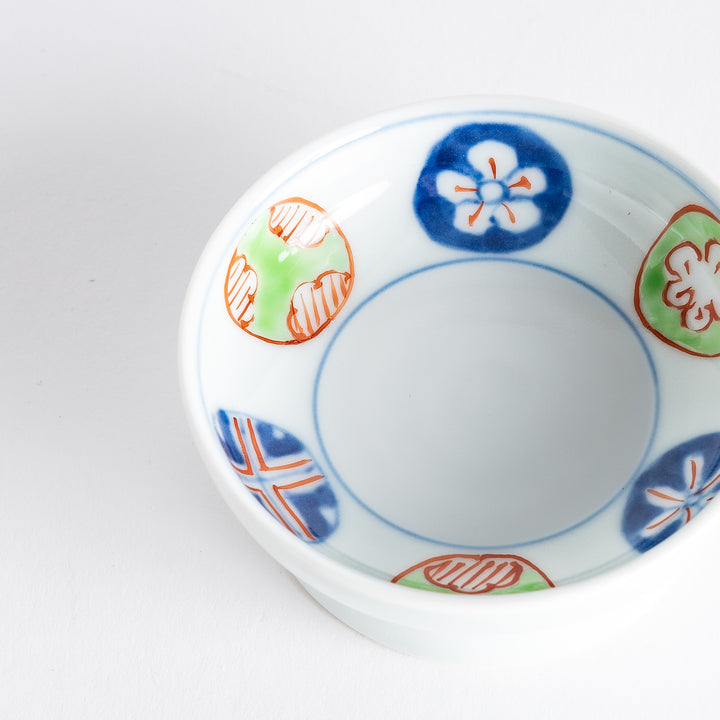 A small raised sauce dish adorned with traditional Japanese motifs, including floral and geometric patterns in red, blue, and green.