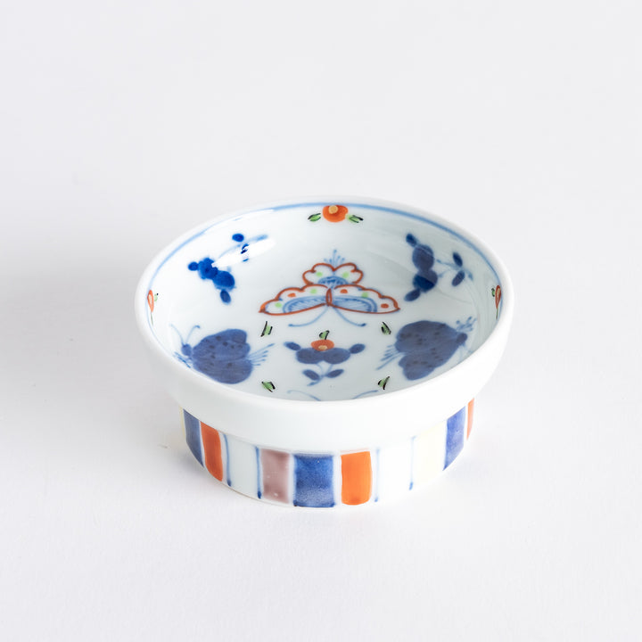 A petite raised sauce dish featuring colorful butterflies and floral designs, with multicolored vertical stripes along the base.