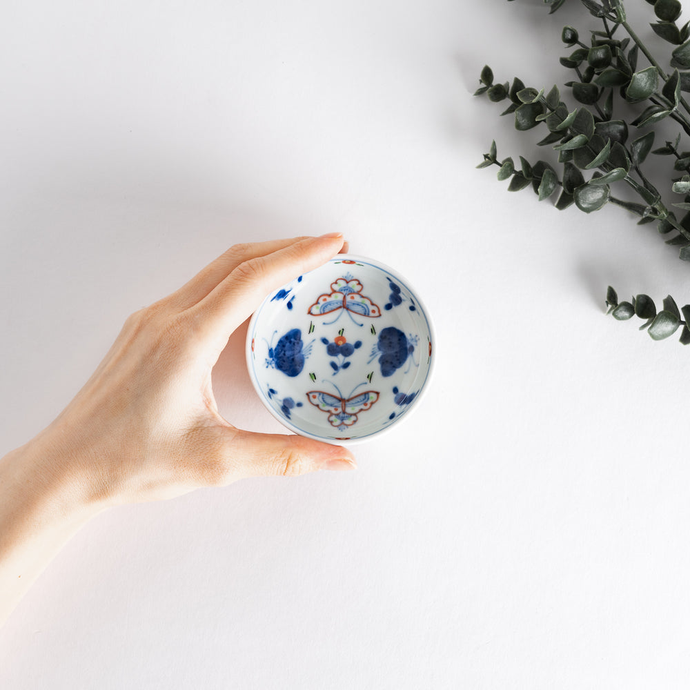 A petite raised sauce dish featuring colorful butterflies and floral designs, with multicolored vertical stripes along the base.