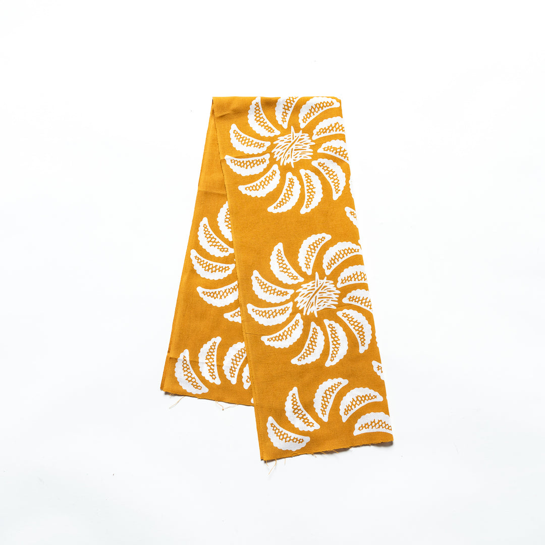 Mustard yellow tenugui adorned with white gyoza patterns forming a floral motif.