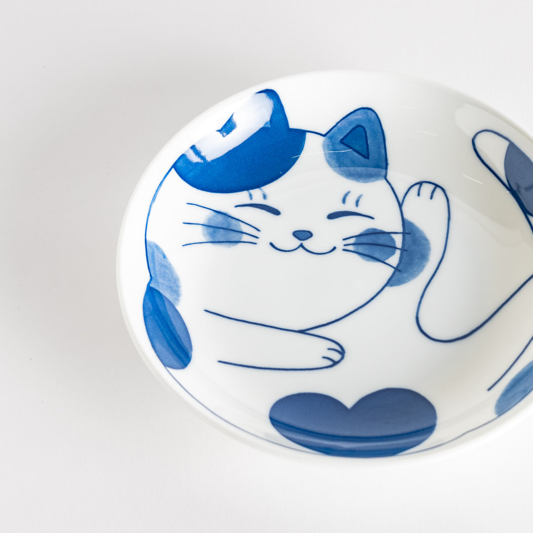 A cereal bowl with a cheerful blue and white cat, playfully kicking its leg up.