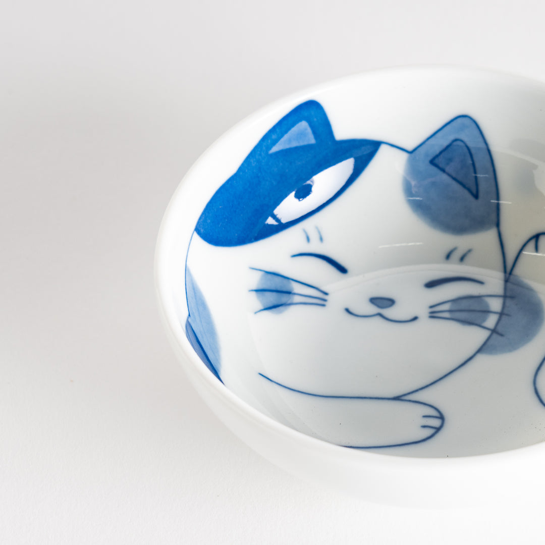 A dessert bowl featuring a playful blue and white cat with a relaxed expression.