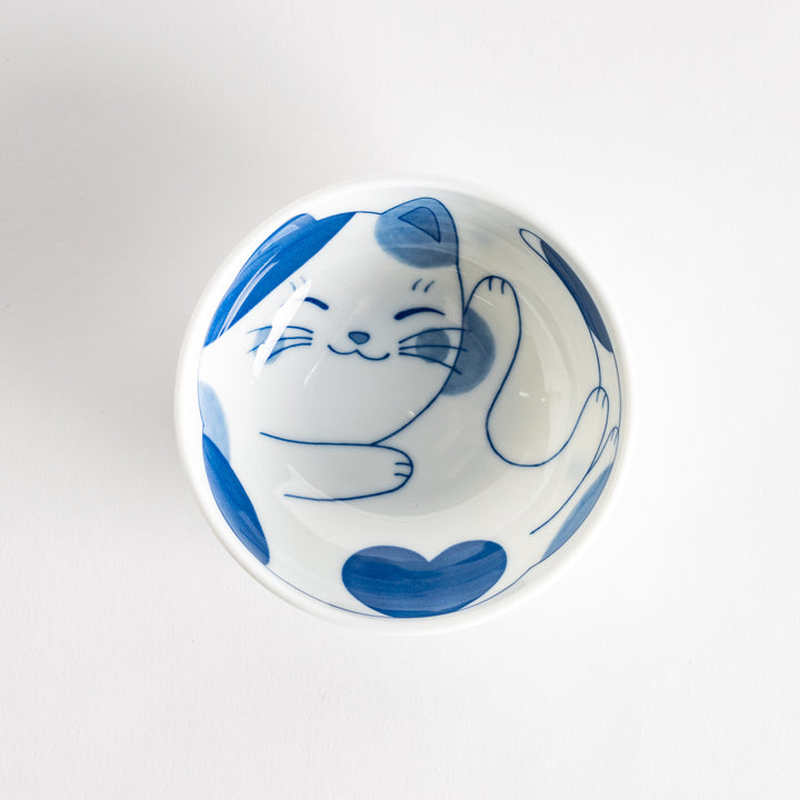 A dessert bowl featuring a playful blue and white cat with a relaxed expression.