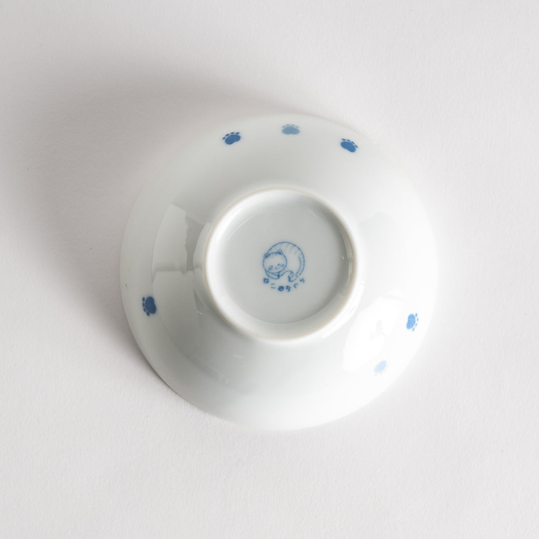 A dessert bowl featuring a playful blue and white cat with a relaxed expression.