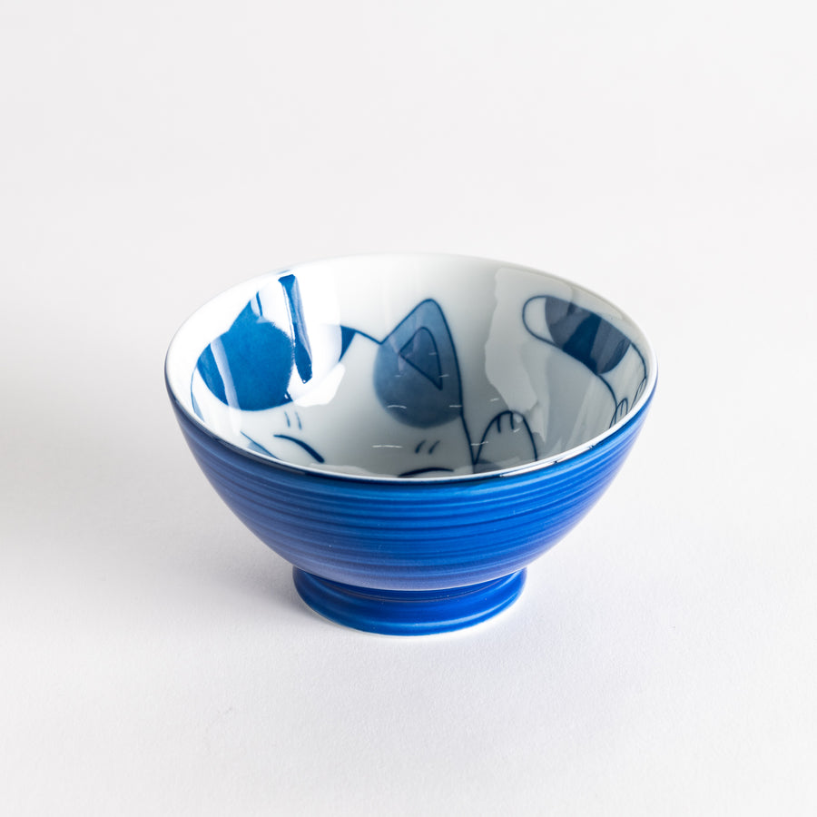 A rice bowl featuring a playful blue and white cat, stretching with a happy expression.