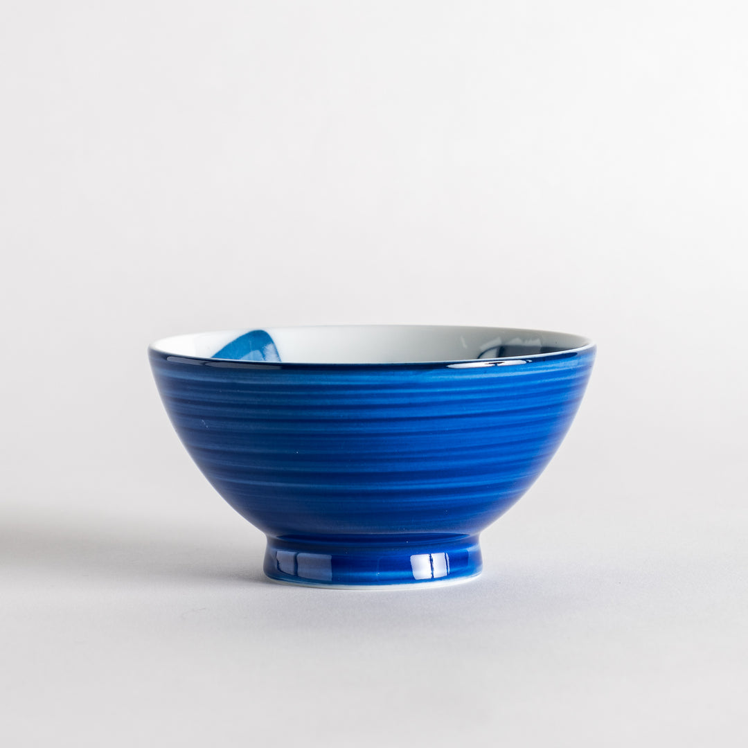 A rice bowl featuring a playful blue and white cat, stretching with a happy expression.