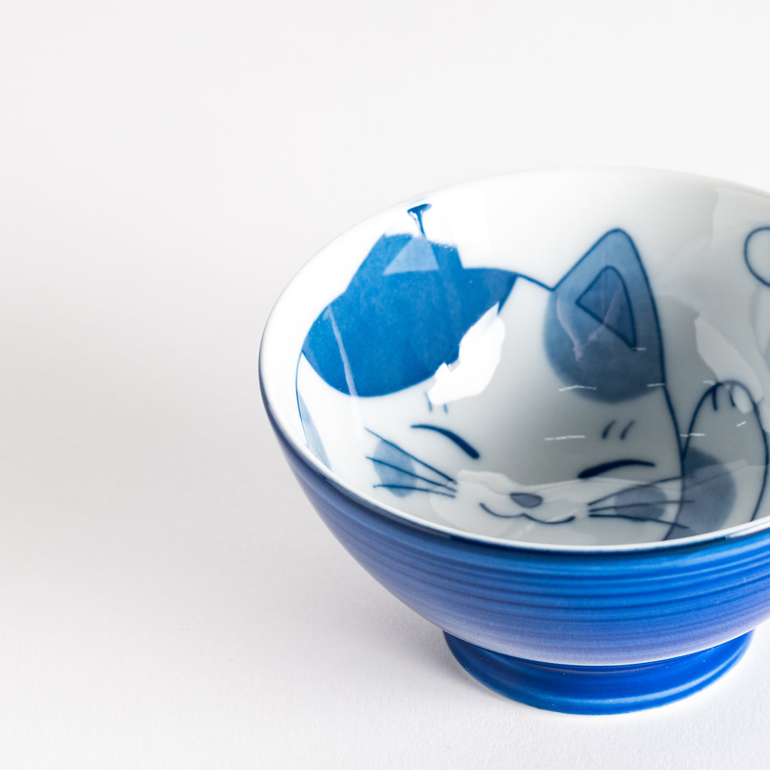 A rice bowl featuring a playful blue and white cat, stretching with a happy expression.