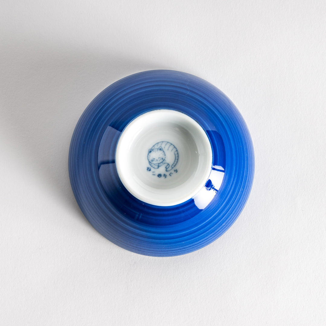 A rice bowl featuring a playful blue and white cat, stretching with a happy expression.