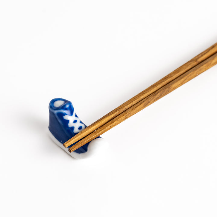 Blue Canvas Sneaker Chopstick Rest holding wooden chopsticks, showcasing its vibrant design and practical functionality.