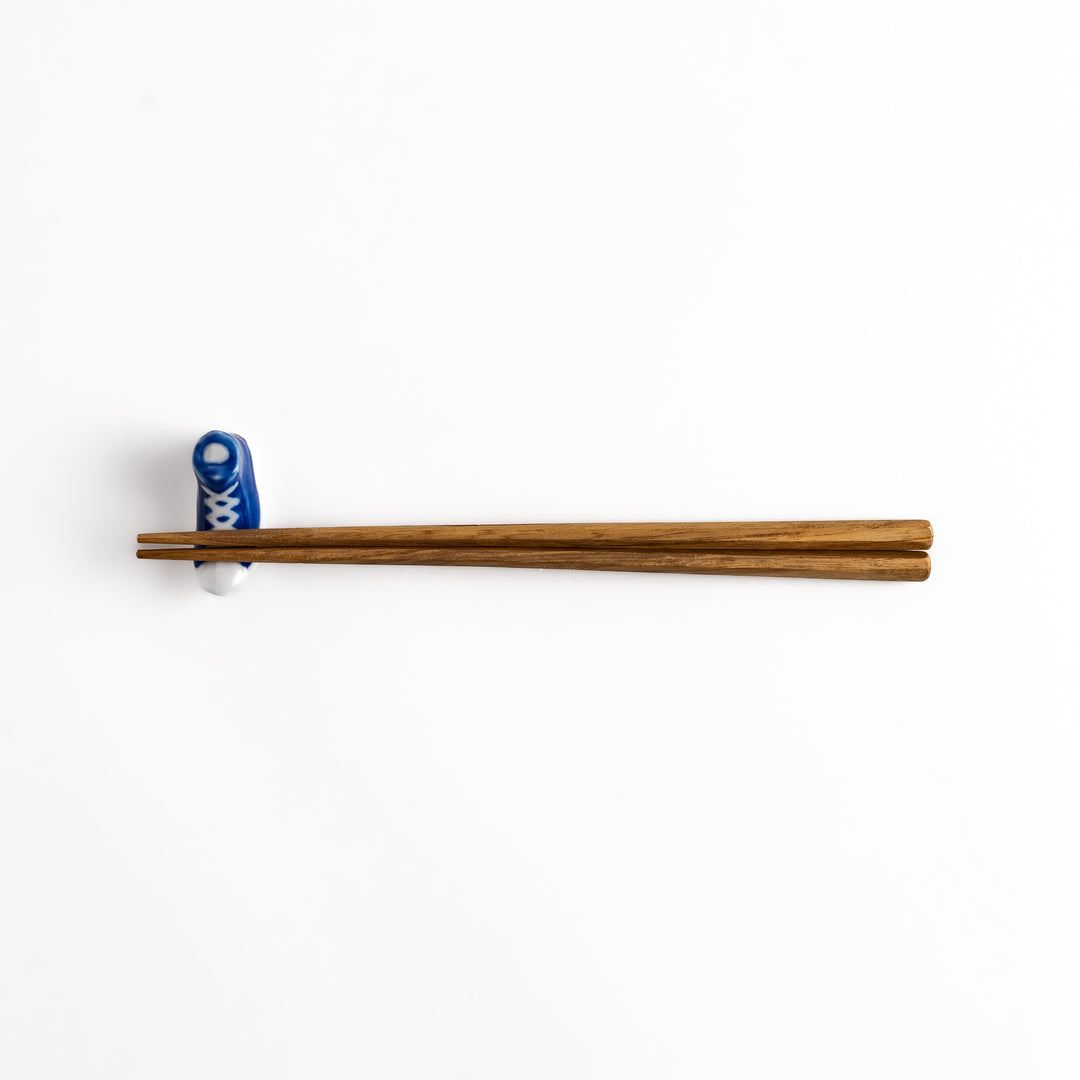 Blue Canvas Sneaker Chopstick Rest holding wooden chopsticks, showcasing its vibrant design and practical functionality.