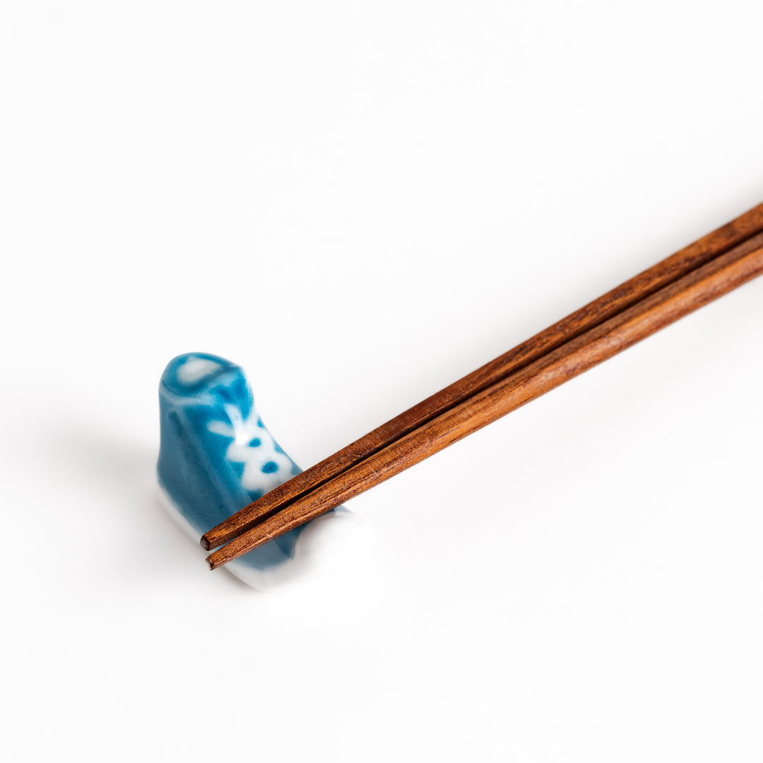 Light Blue Canvas Sneaker Chopstick Rest holding wooden chopsticks, showcasing its vibrant design and practical functionality.